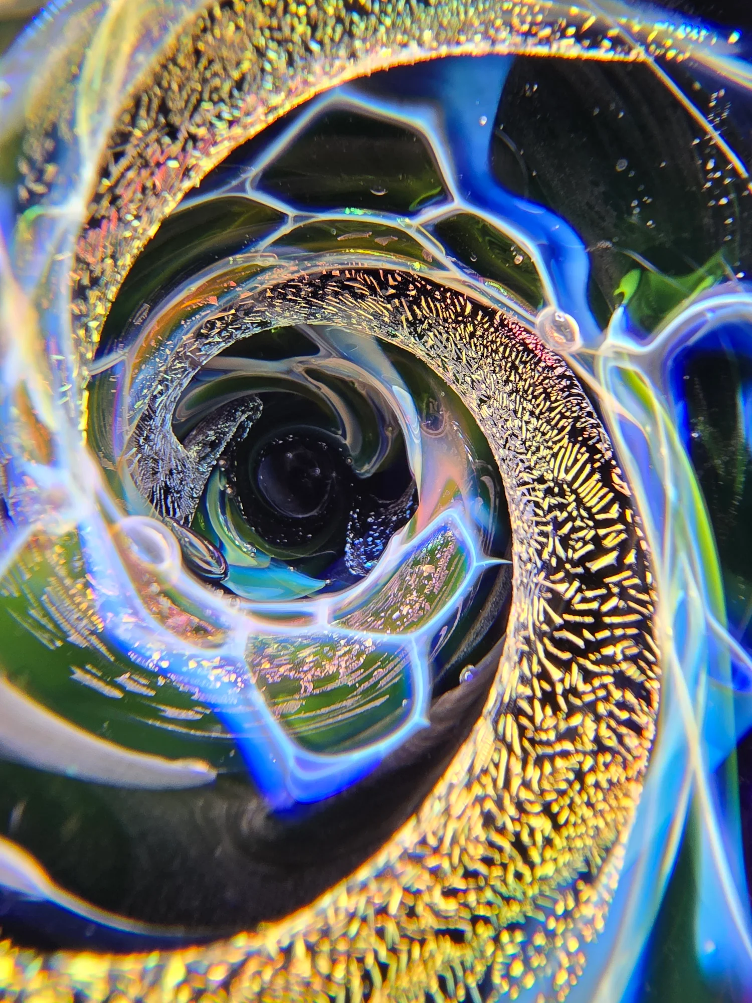 Macro detail of a dichroic glass marble in gold, blue and green