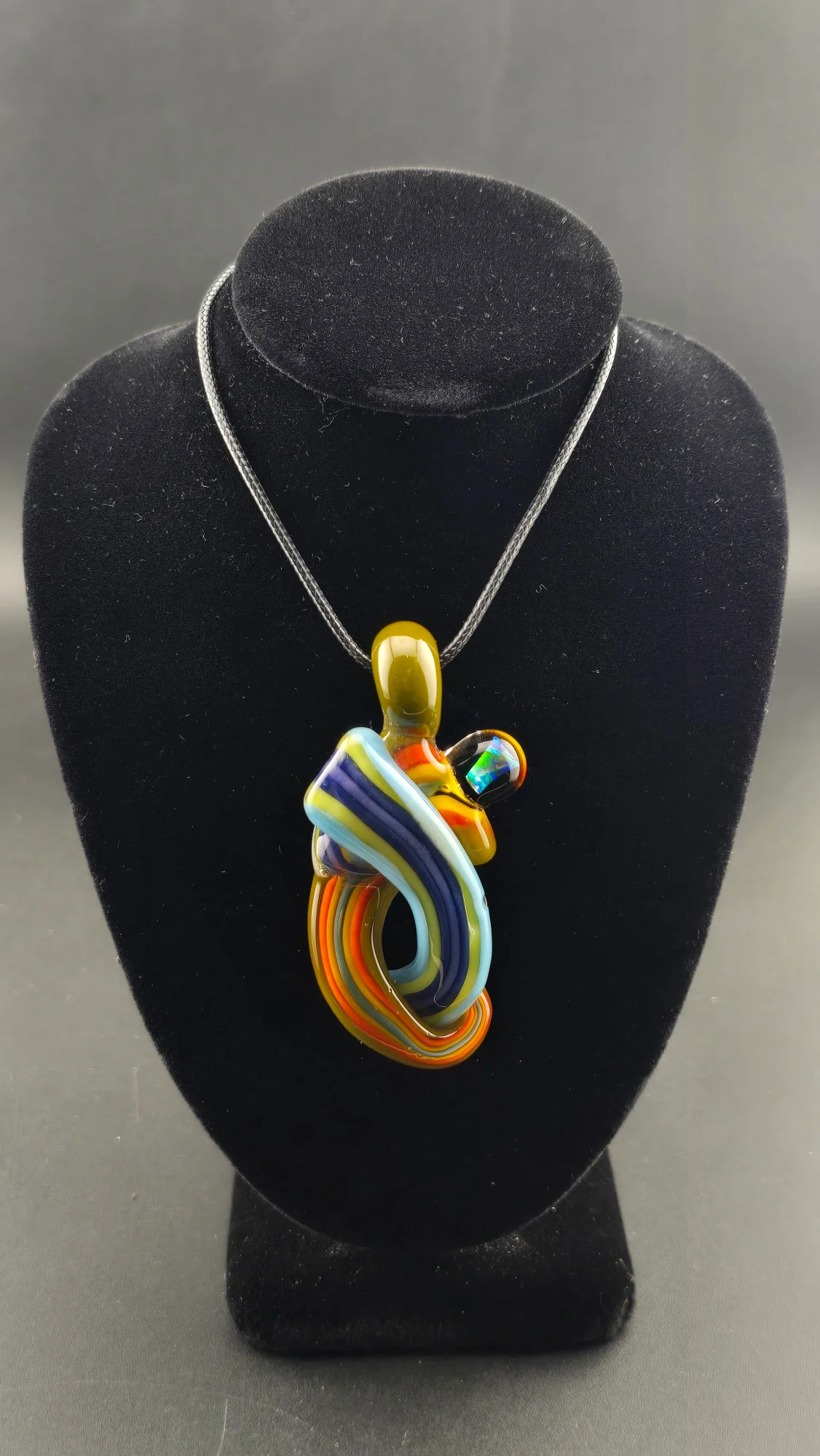 Color Current, a hand-blown glass pendant by Jared Omas with sweeping ribbons of blue, yellow, orange and purple and a bright opal accent