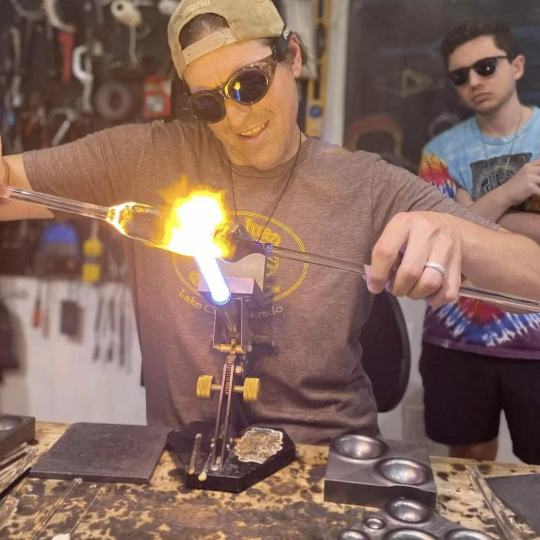 Jared shaping molten glass at the torch during a class